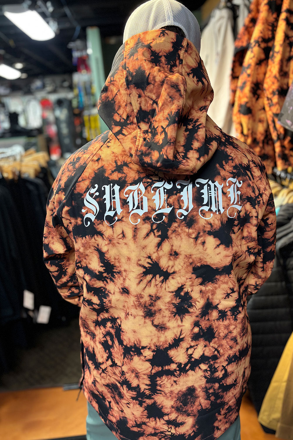 Person wearing a tie-dye hoodie with 'Sublime' text in a store setting