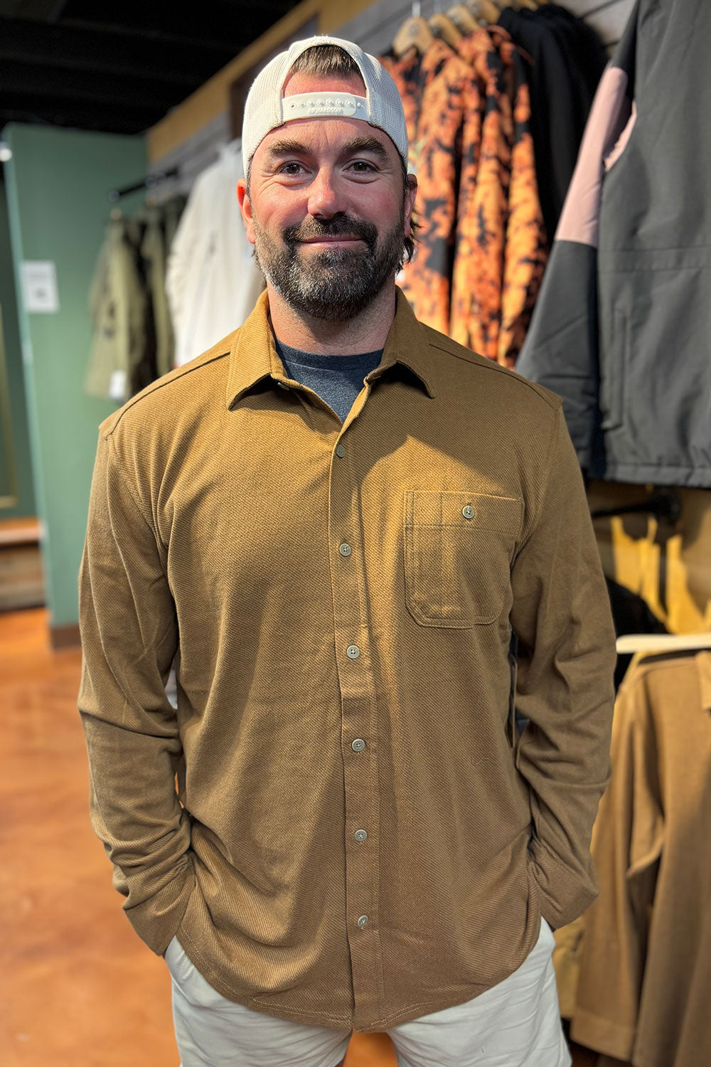 Man wearing a brown shirt and cap in a clothing store