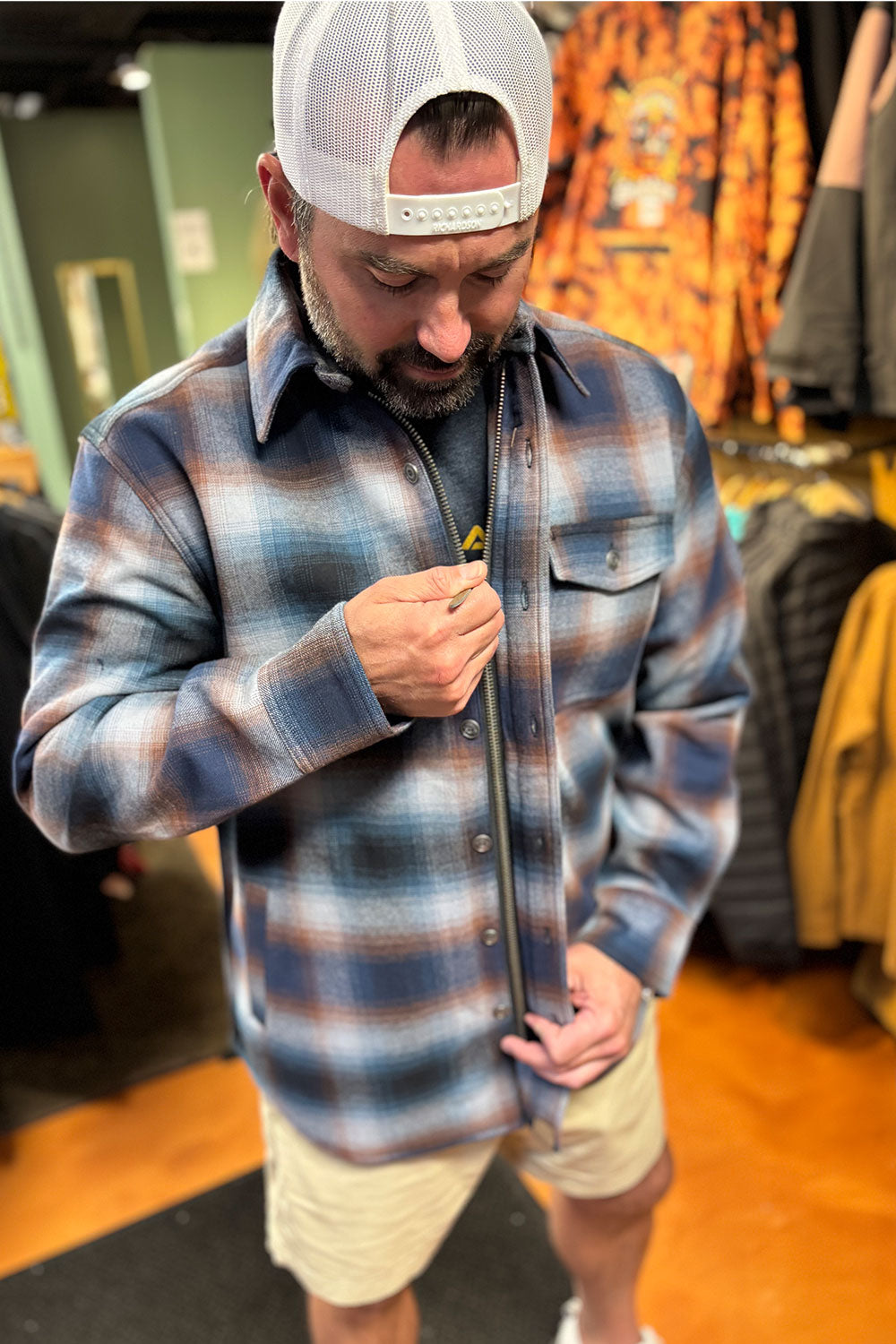 Man wearing a plaid shirt and cap in a store setting