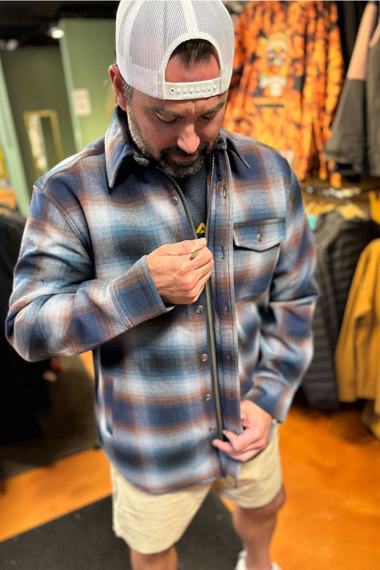 Man wearing a plaid shirt and cap in a store setting