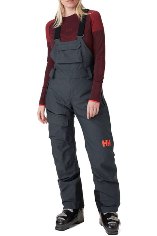 Person wearing navy bib overalls with a red logo on a white background