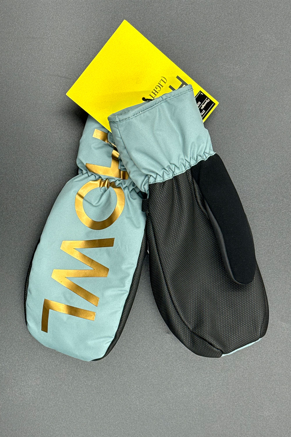 Pair of light blue mittens with gold lettering on a gray background