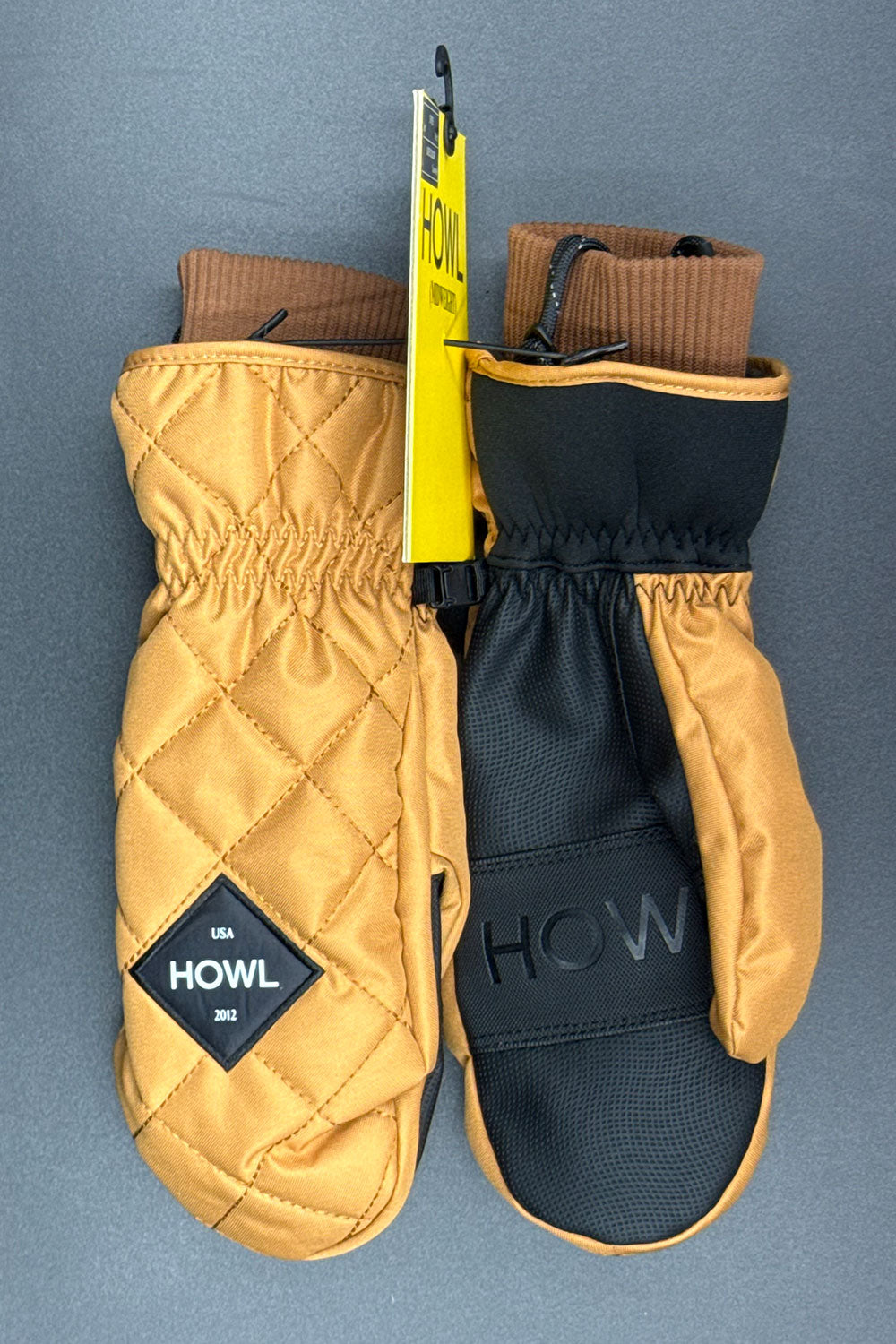 Pair of quilted mittens with a visible brand logo on a gray background