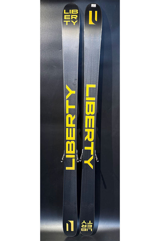 Two Liberty skis with yellow text on a dark background