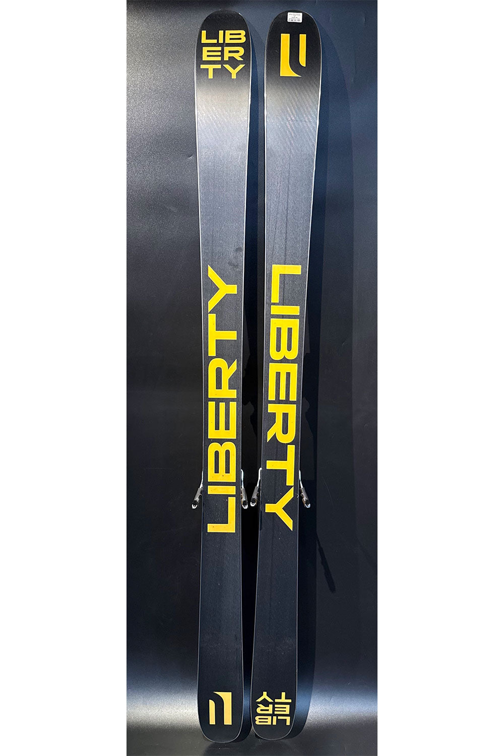 Two Liberty skis with yellow text on a dark background