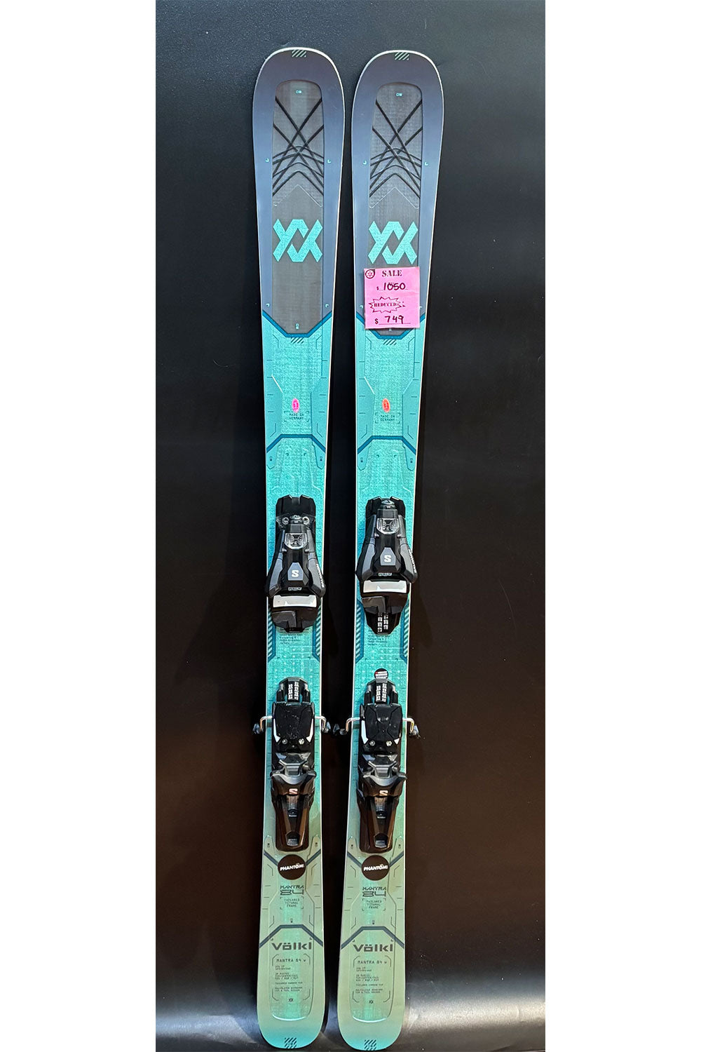 Pair of teal skis with bindings on a dark background