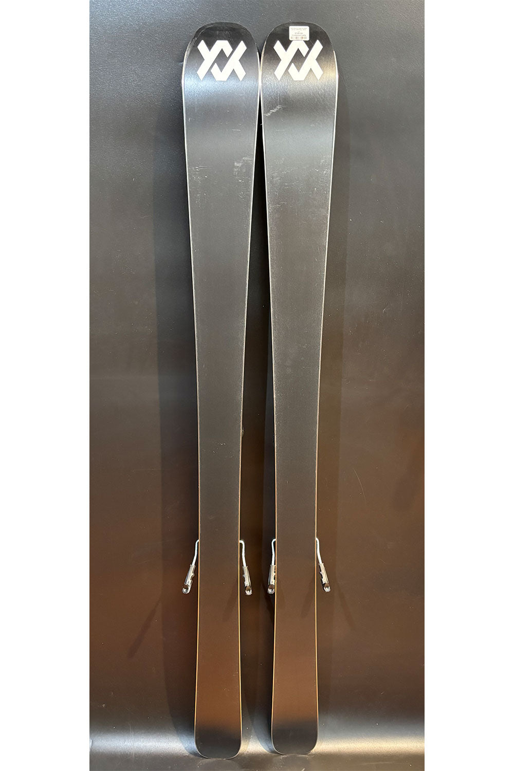 Two silver skis with a brand logo on a metallic background