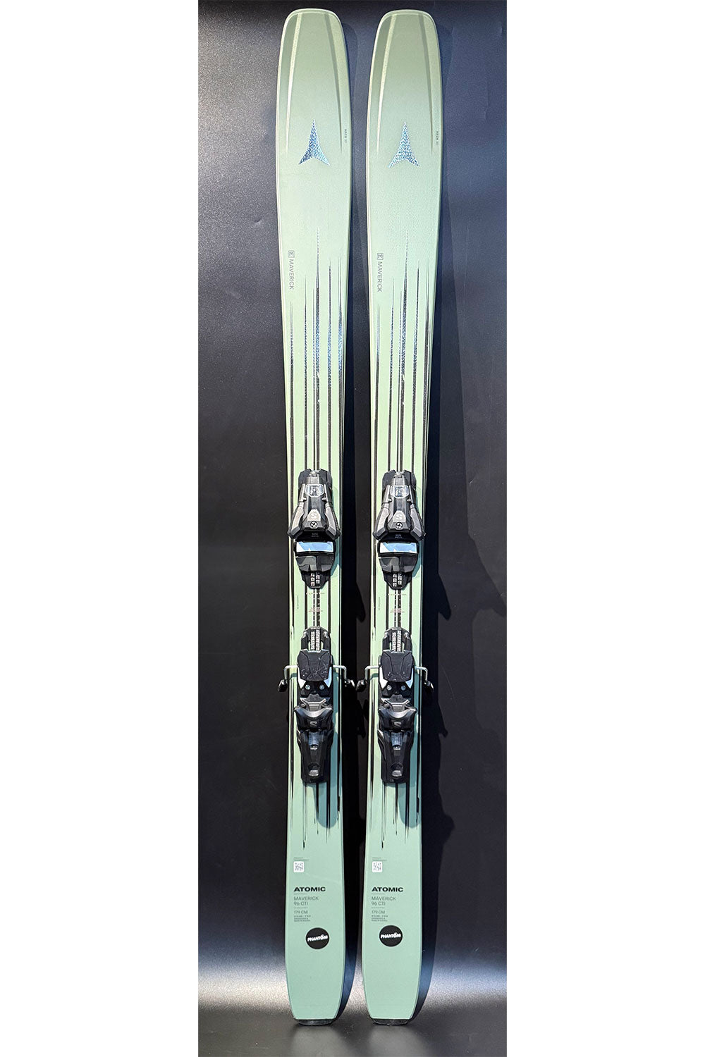 Pair of light green skis with bindings on a dark background