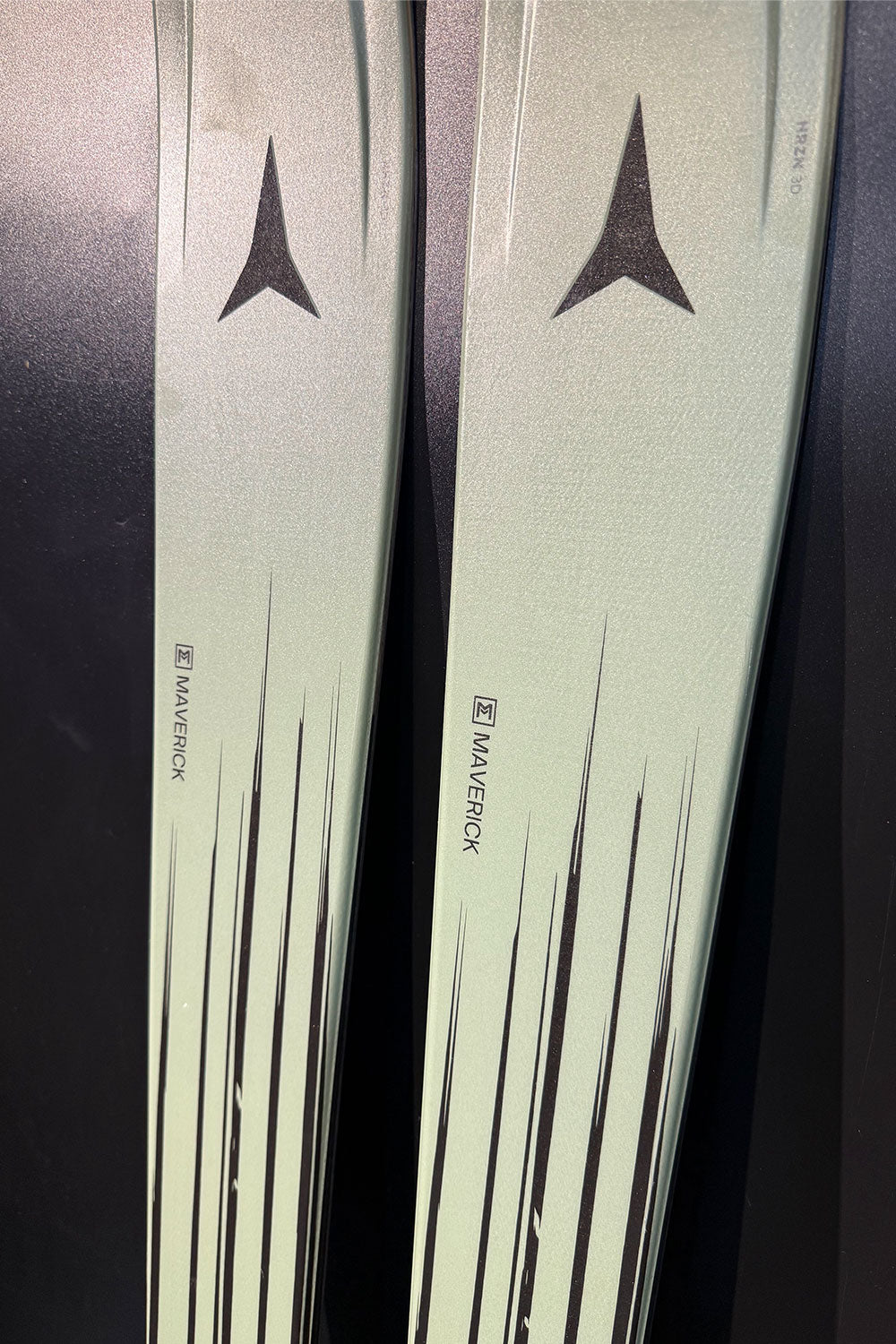 Two skis with a brand logo on a dark background