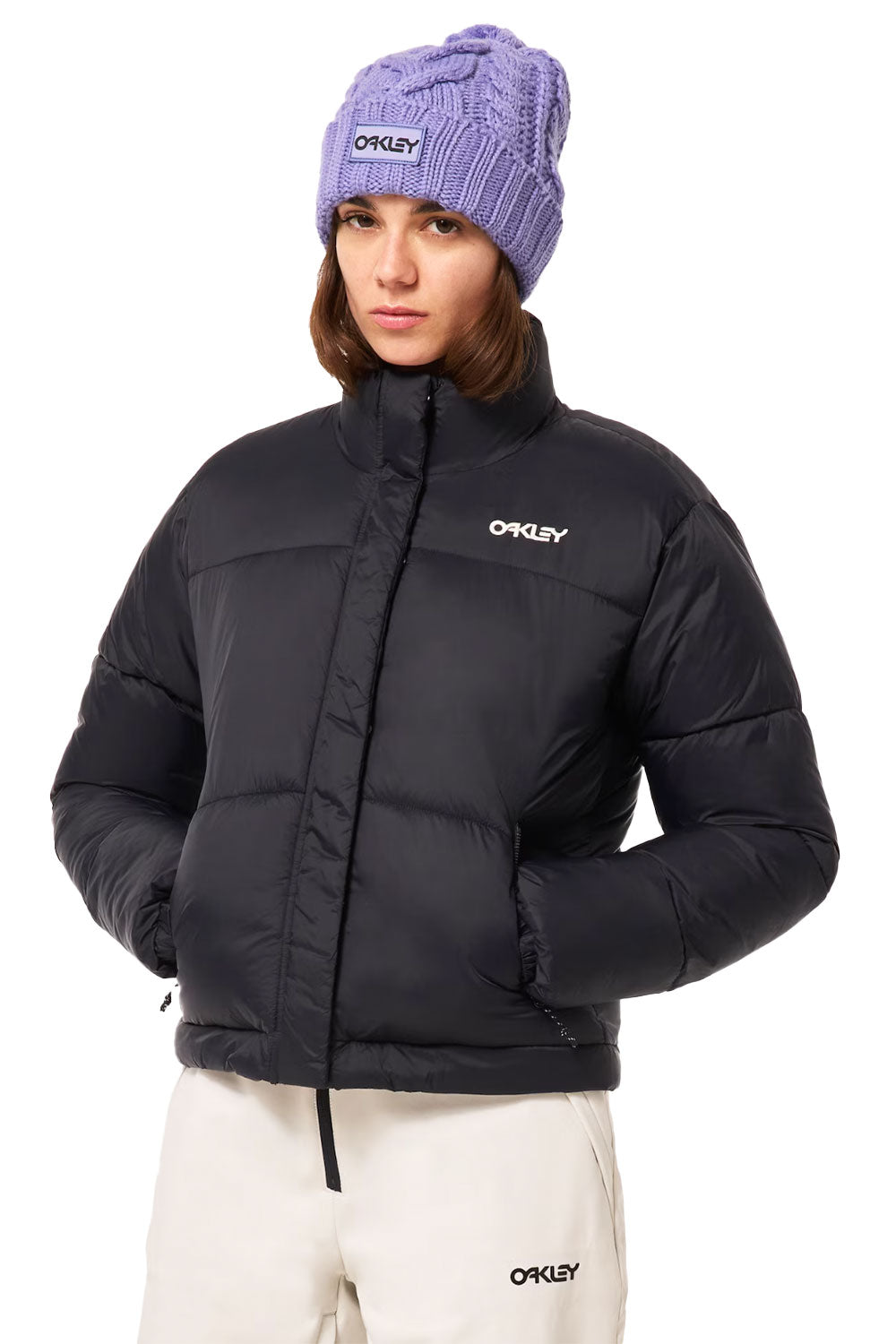Person wearing a black puffer jacket and purple beanie with 'Oakley' logo on a white background