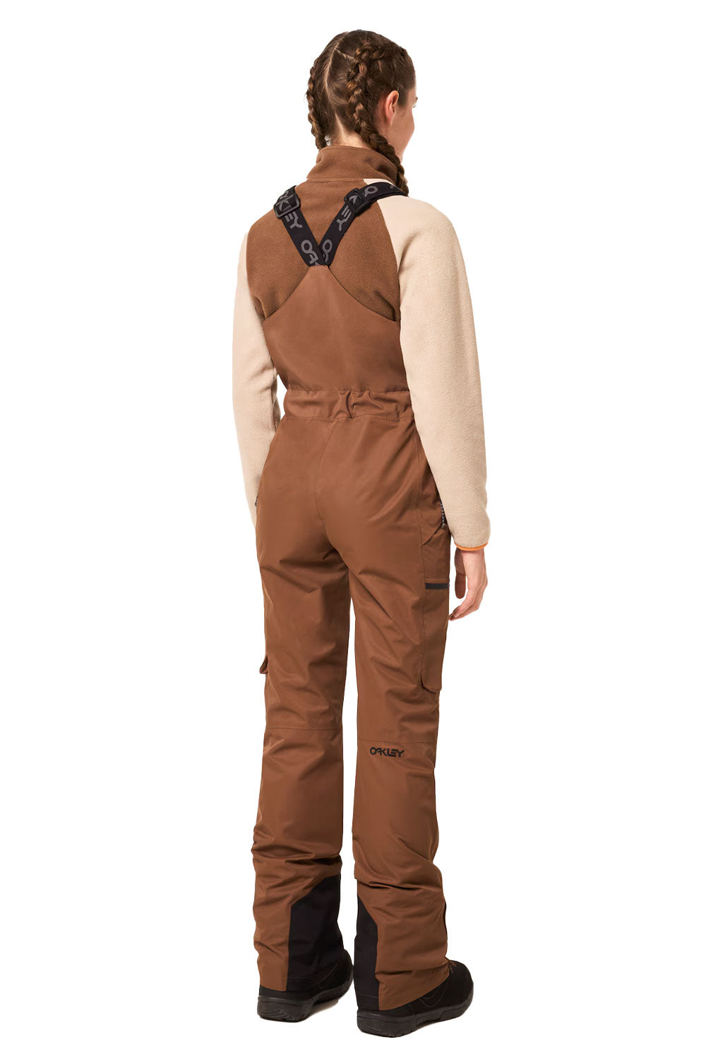 Person wearing brown bib overalls on a white background