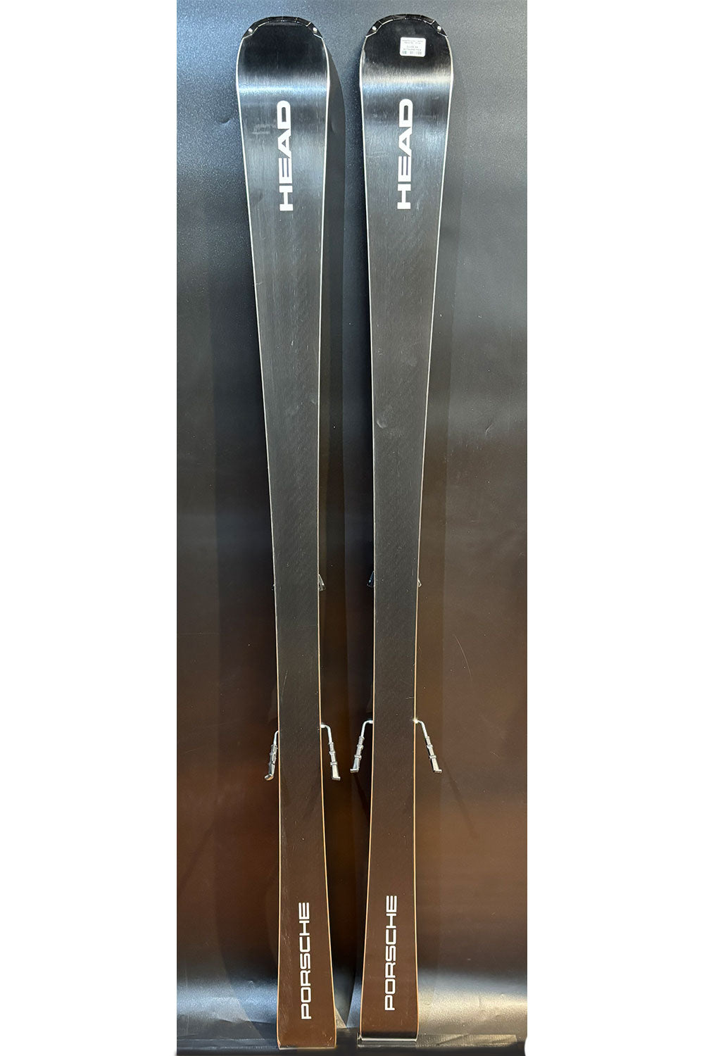 Two silver skis with 'HEAD' branding on a reflective surface
