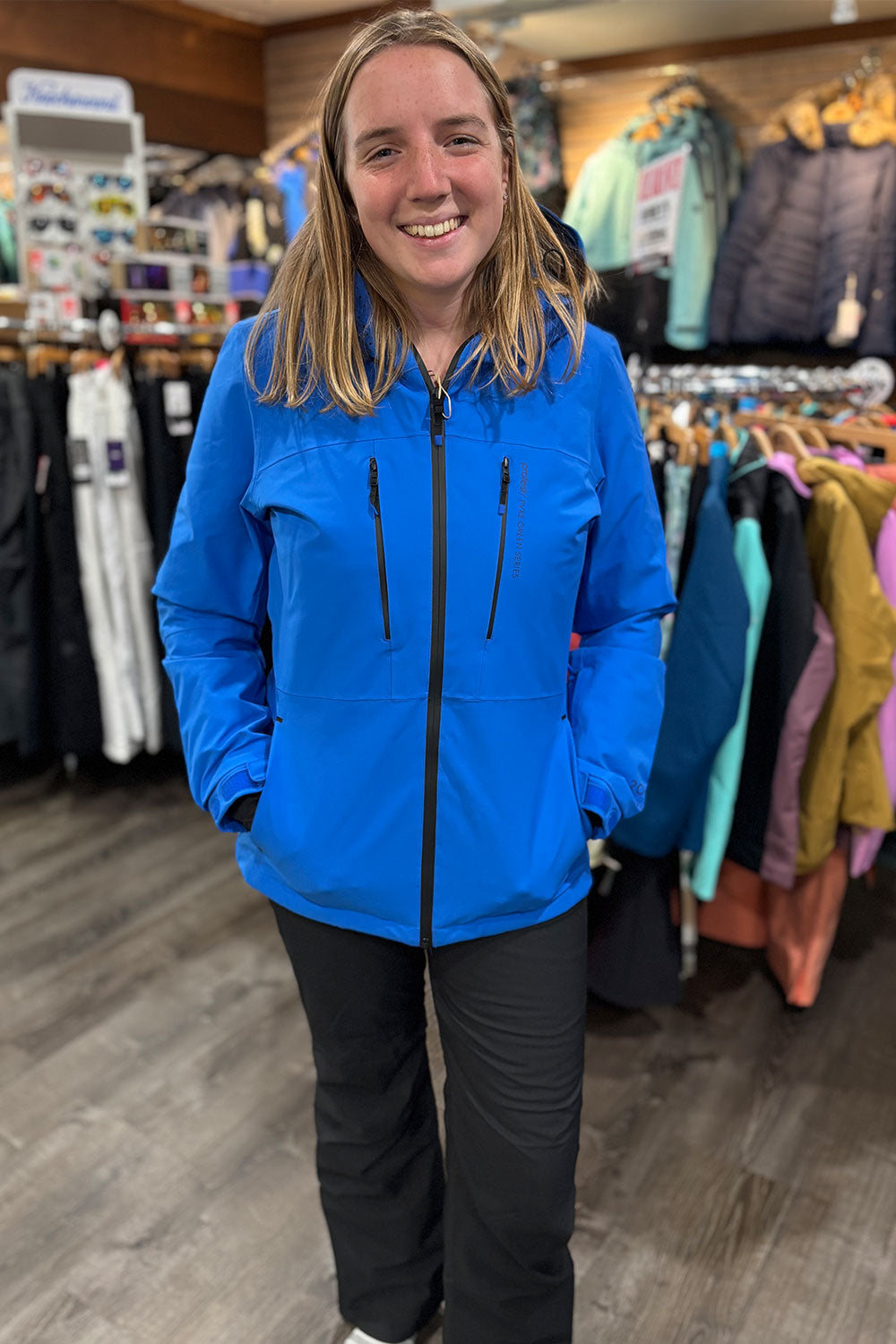 Person wearing a blue jacket in a store with clothing racks in the background