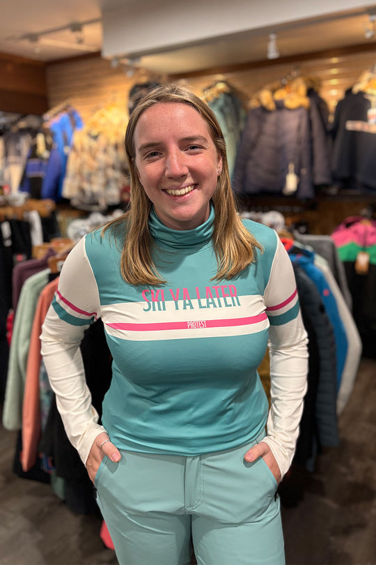 Person wearing a teal and white outfit with 'Ski Ya Later' text in a clothing store.