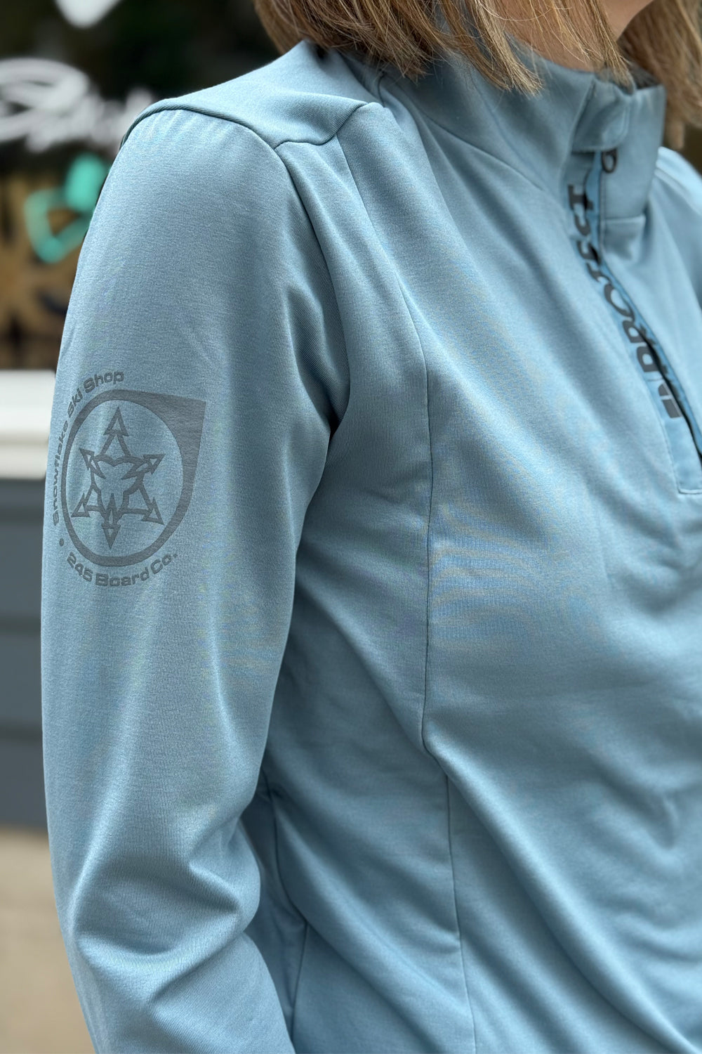 Light blue jacket with a logo on the sleeve, worn by a person.