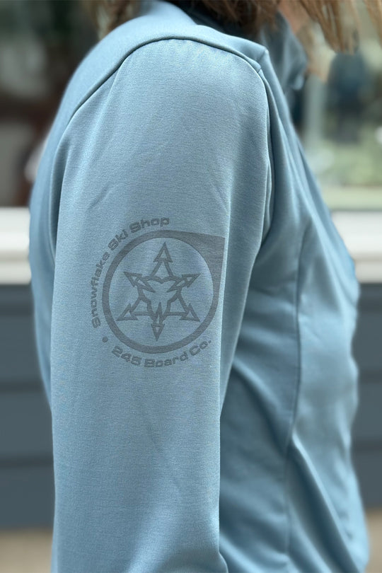 Light blue hoodie with a star logo and text on the sleeve, blurred background