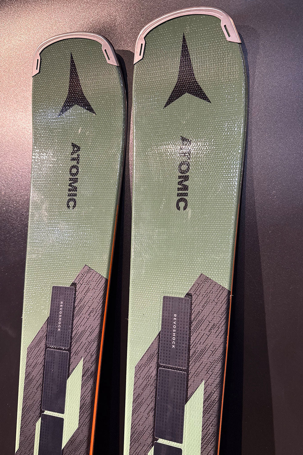 Two green Atomic skis on a dark surface