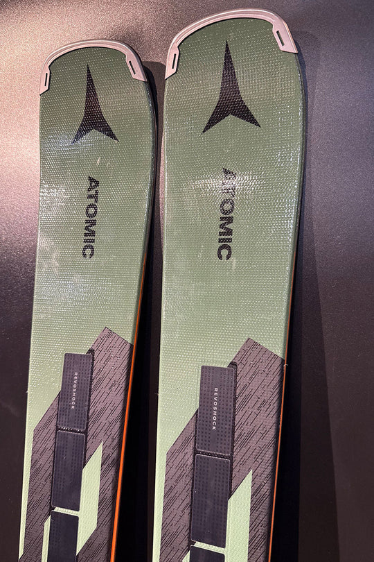 Two green Atomic skis on a dark surface