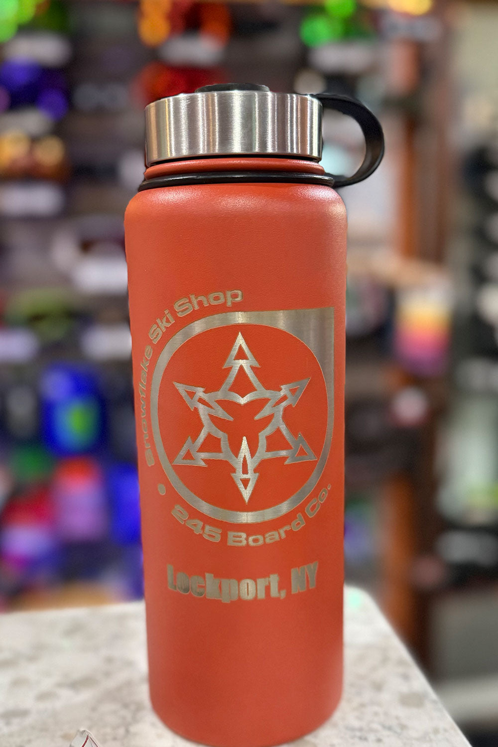 Orange water bottle with a star design and text on a blurred background