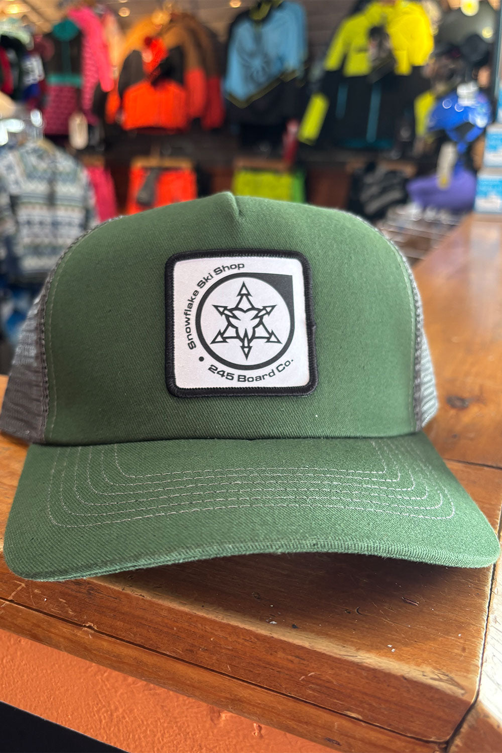 Green trucker hat with a logo on a wooden surface with a store background