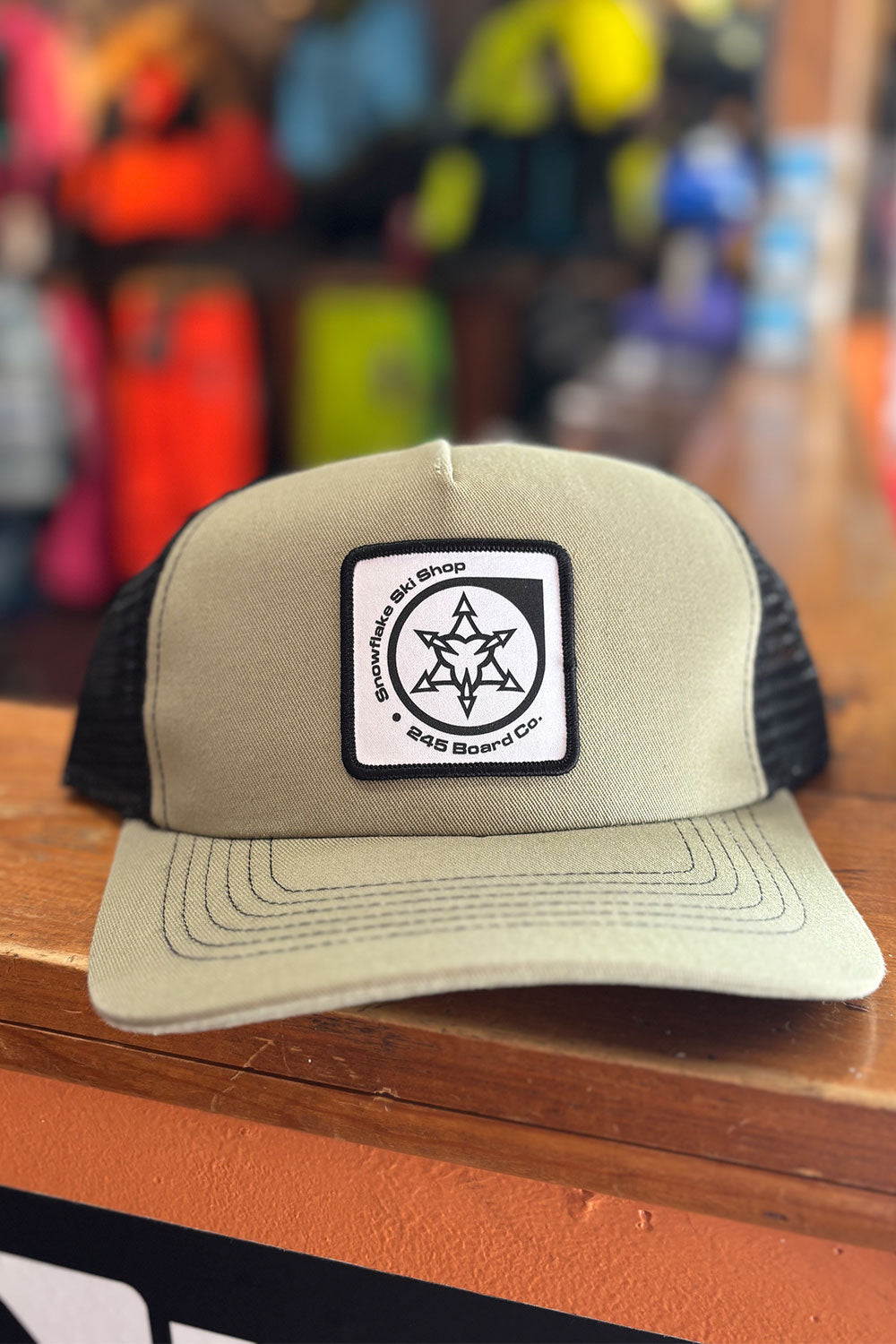 Beige trucker hat with a black and white logo on a wooden surface