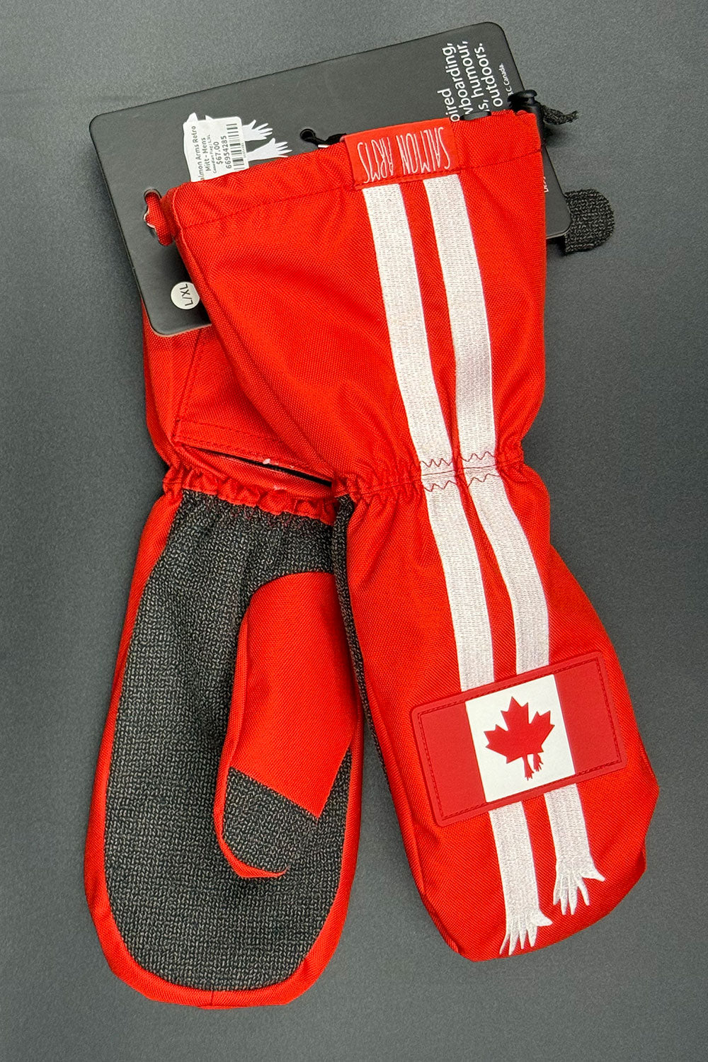 Red mittens with white stripes and a maple leaf design on a gray background