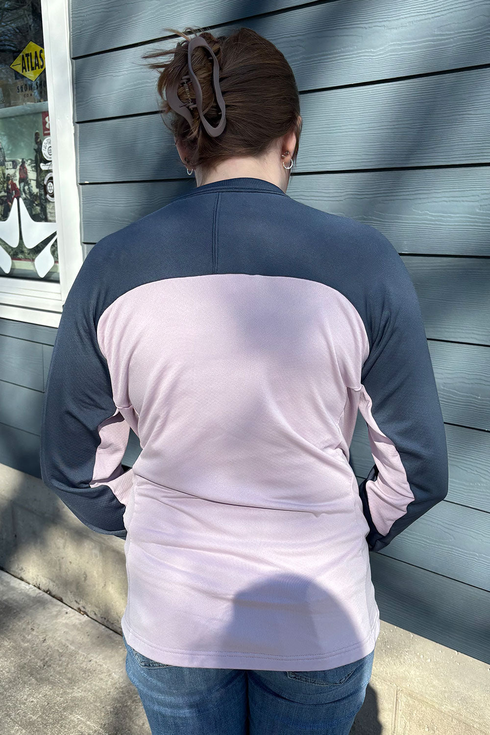 Person wearing a two-tone shirt with navy and light pink colors, standing against a blue wall.