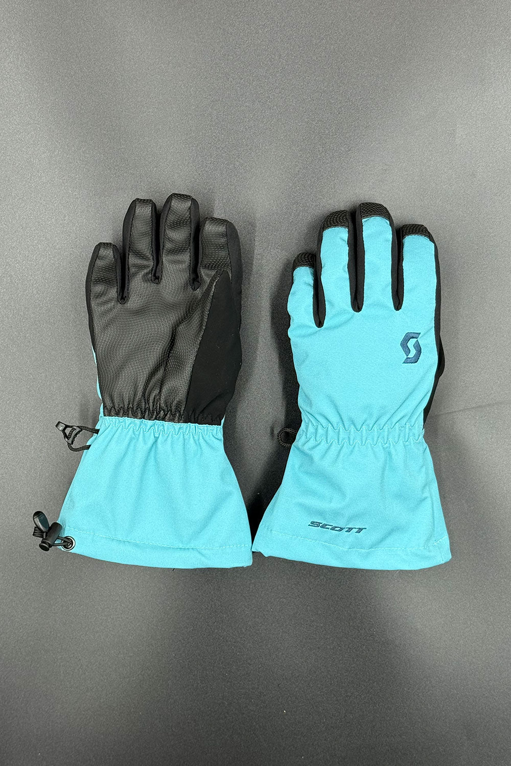 Pair of turquoise gloves with black cuffs on a gray background