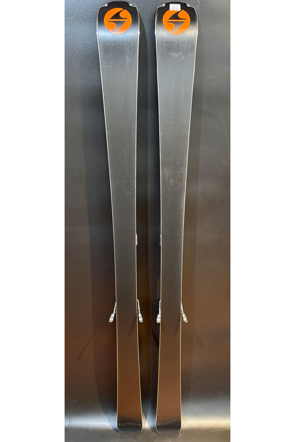 Two silver skis with a logo on a reflective surface