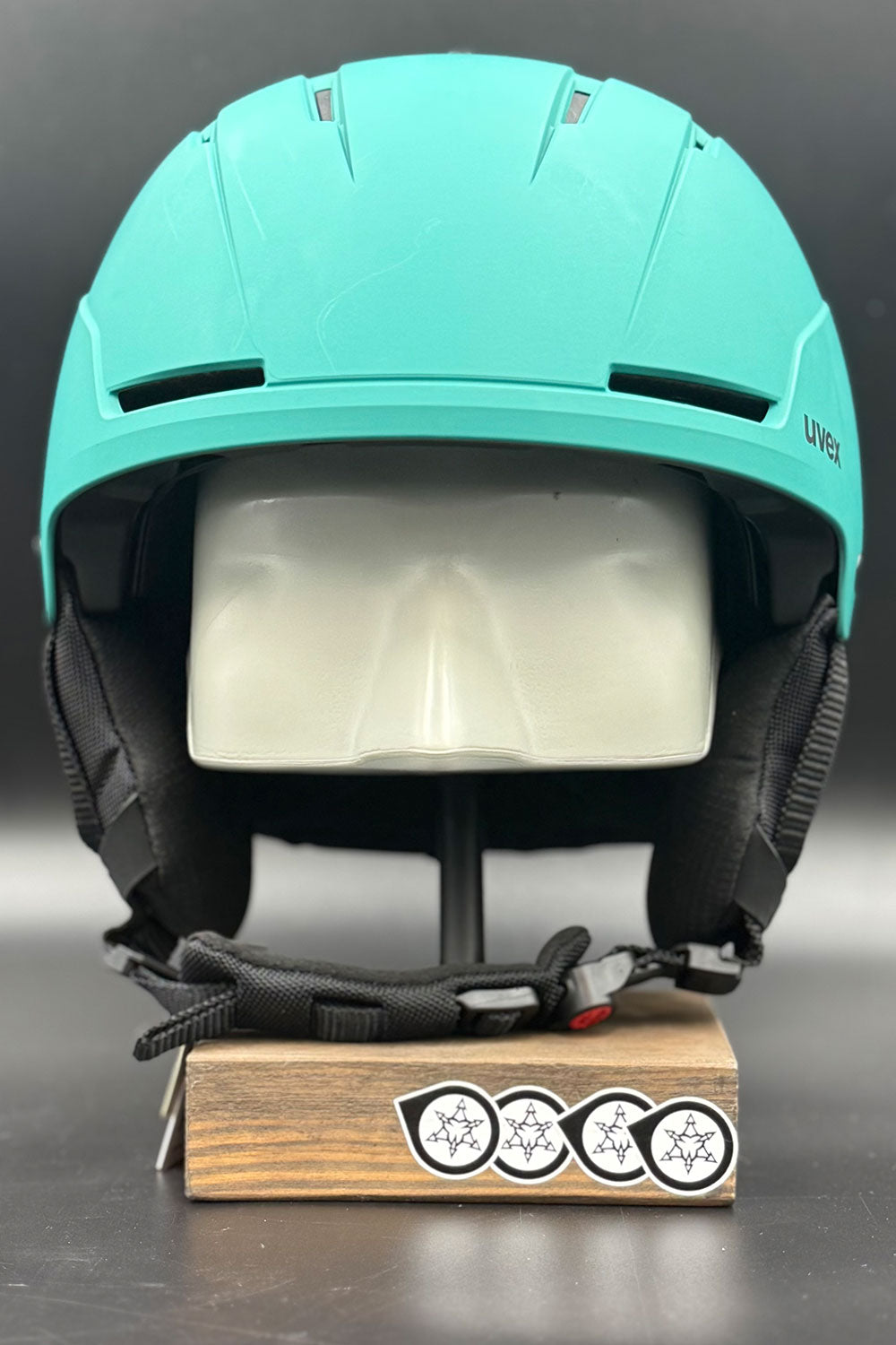 Turquoise helmet on a wooden block against a dark background