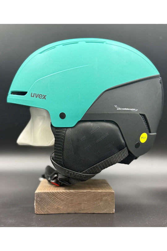 Turquoise and black helmet with Uvex branding on a wooden block against a dark background