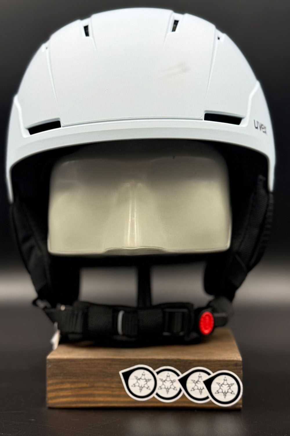 White helmet on a wooden block with visible branding against a dark background